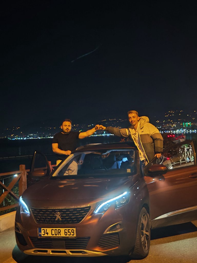 Fist bump with a friend over a car at night