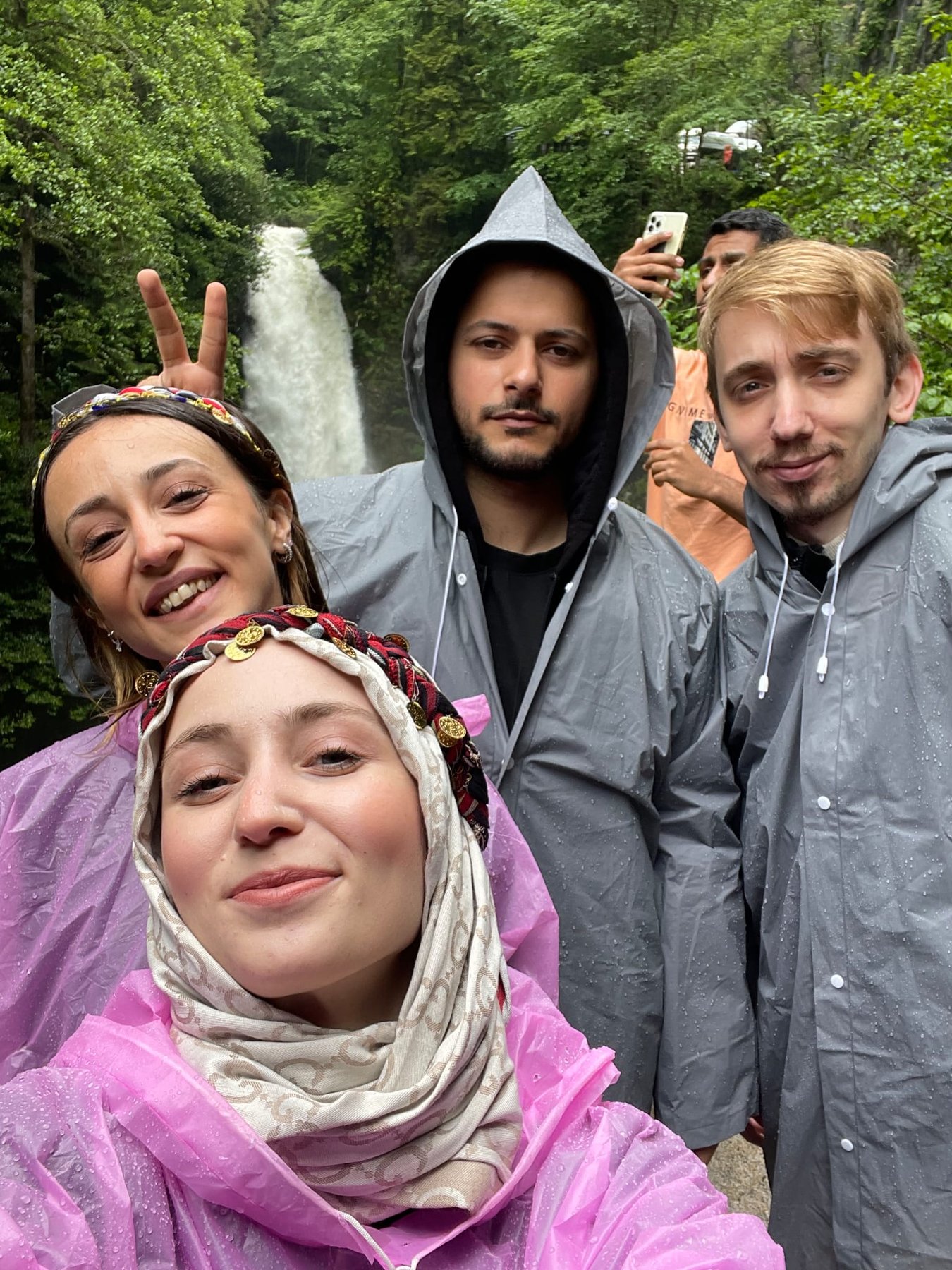 Friends in rain ponchos at a waterfall